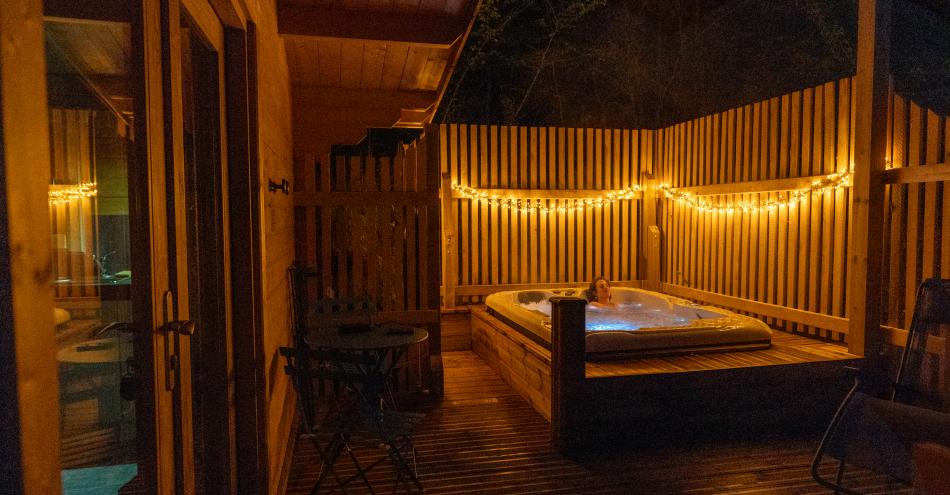 photo représentant une personne se baignant dans le jacuzzi la nuit. on y voit un éclairage chaleureux
