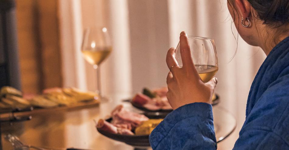 photo ambiance cocooning aux Lodges de Valières, Chorges Alpes du sud. On y voit une femme en demi profil un verre à la main avec une planche apéro posée devant elle