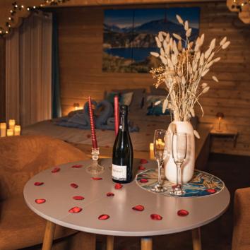 photo de prestation romantique des Lodges de Valière : pétales de roses, bouteille et 2 verres, bouquet de fleurs